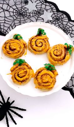 some food is on a white plate with black spider legs and lace doily in the background