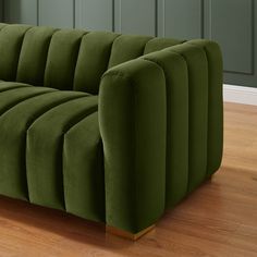 a green couch sitting on top of a hard wood floor