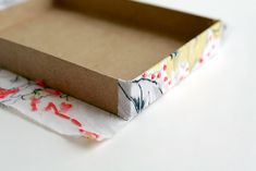 an empty box sitting on top of a white table next to a piece of cloth