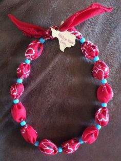 a red and blue beaded bracelet on a brown leather surface with a white tag that says happy valentine's day