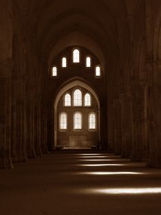 an empty cathedral with light coming through the windows and stone columns on either side of the room