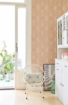 a white chair sitting in front of a window next to a wallpapered wall