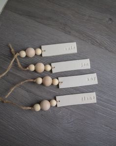 four tags are attached to string on a table with wood beads and twine around them