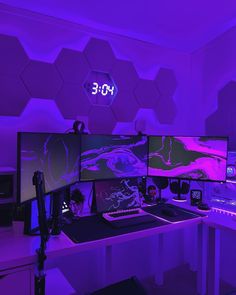 two computer monitors sitting on top of a desk in front of purple lights and hexagon tiles