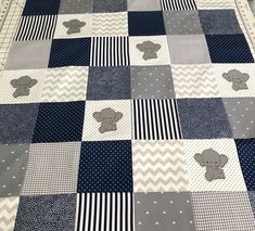 a baby quilt with elephants on it in blue and grey colors, sitting on a bed