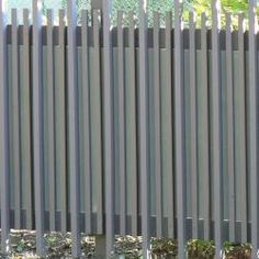 an orange fire hydrant in front of a metal fence with vertical slats on it