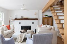 a living room filled with furniture and a fire place under a stair case next to a window