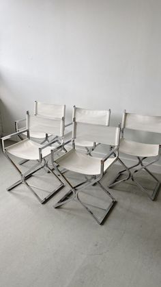 four white chairs sitting next to each other in a room with no one on the floor