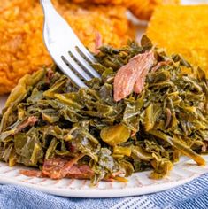 a white plate topped with collard greens next to fried chicken