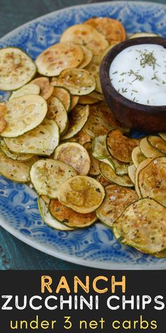 a blue and white plate topped with sliced zucchini chips next to a bowl of ranch dressing