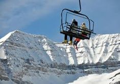 two people on a ski lift above the snow covered mountains