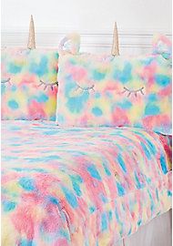 a bed topped with two pillows covered in rainbow colored blankets and unicorn ears on top of it