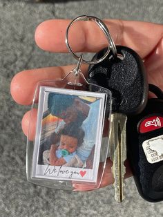 a person holding two keys in their left hand and a car keychain with a photo on it