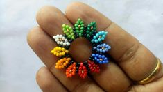 a hand holding a small multicolored beaded ring