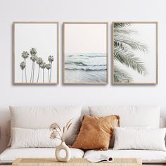 three framed art prints on the wall above a couch in a living room with white furniture