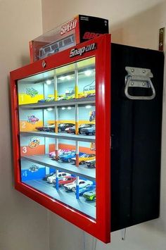 a toy vending machine with cars in it's display case on the wall