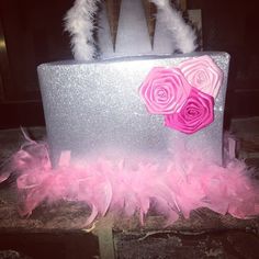 a silver box with pink flowers and feathers