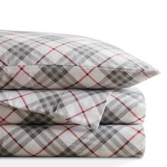 two pillows stacked on top of each other with plaid print and red trimmings