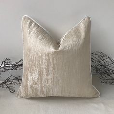 a white pillow sitting on top of a bed next to dried branches in the background