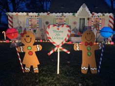 two gingerbread men standing in front of a house decorated with candy canes and candies