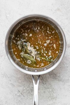 a pot filled with some kind of food on top of a white countertop next to a metal spoon