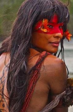 a woman with red face paint and flowers in her hair