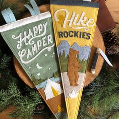 two happy camper towels hanging from a christmas tree with pine cones in the background