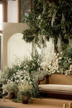 white flowers and greenery are on display in front of a mirror, next to a bench