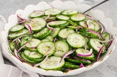 a white bowl filled with cucumbers and onions on top of a gray table