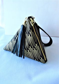 a small black and white bag with tassels on the front, sitting on a blue surface