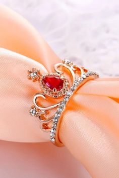 a ring with a large red stone on it sitting on top of a pink napkin