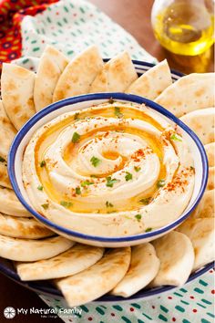 hummus and pita chips on a plate with dipping sauce in the middle, ready to be eaten