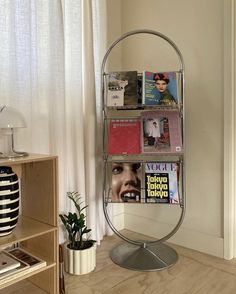 a magazine rack with magazines on it next to a lamp and a potted plant