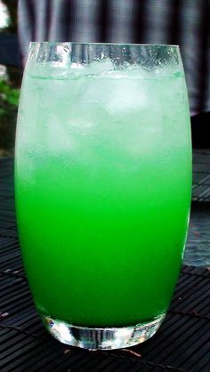 a green drink sitting on top of a table next to a metal grate covered in grass