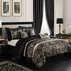 a bedroom with black and white bedding in the middle of it, along with two lamps on either side of the bed