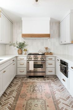 a kitchen with white cabinets and an area rug on the floor in front of the stove