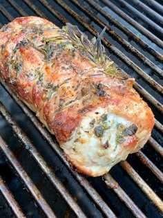 a piece of meat is being cooked on the bbq grill with rosemary sprigs