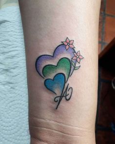 a small tattoo on the wrist of a girl with hearts and flowers in it's center