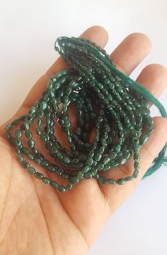 a hand holding some green beads in it's palm and the beading is very long