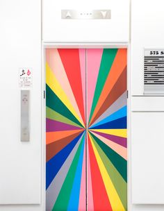 a colorful door is open on a white wall