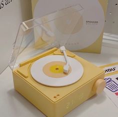 a yellow record player sitting on top of a table next to a white disc jockey