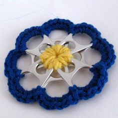 a crocheted brooch with a yellow center and two blue circles around it