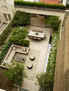 an aerial view of a courtyard with tables and chairs surrounded by greenery on the roof