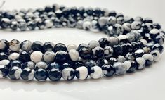 two strands of black and white beads on a white surface with one strand in the middle