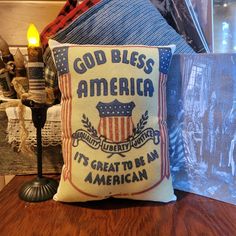 an american flag pillow sitting on top of a wooden table next to a candle and other items