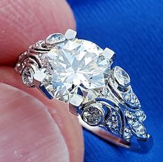 a close up of a person's hand holding a ring with a diamond in it