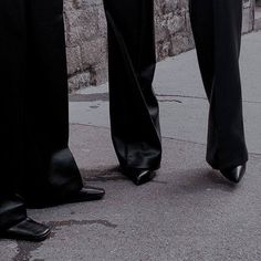 two people standing on the sidewalk with their legs crossed