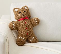 a brown teddy bear sitting on top of a white couch next to a red bow tie