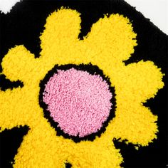 a black and yellow rug with a pink flower on it's center, in the shape of a sunflower