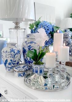 blue and white vases with candles on a tray in front of a mirror table